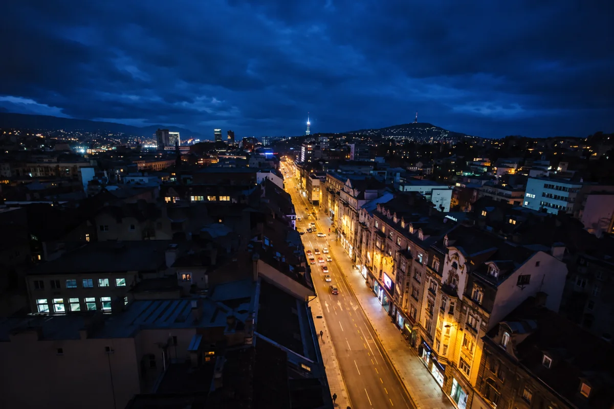 Sarajevo rooftops and illuminated city street at blue hour